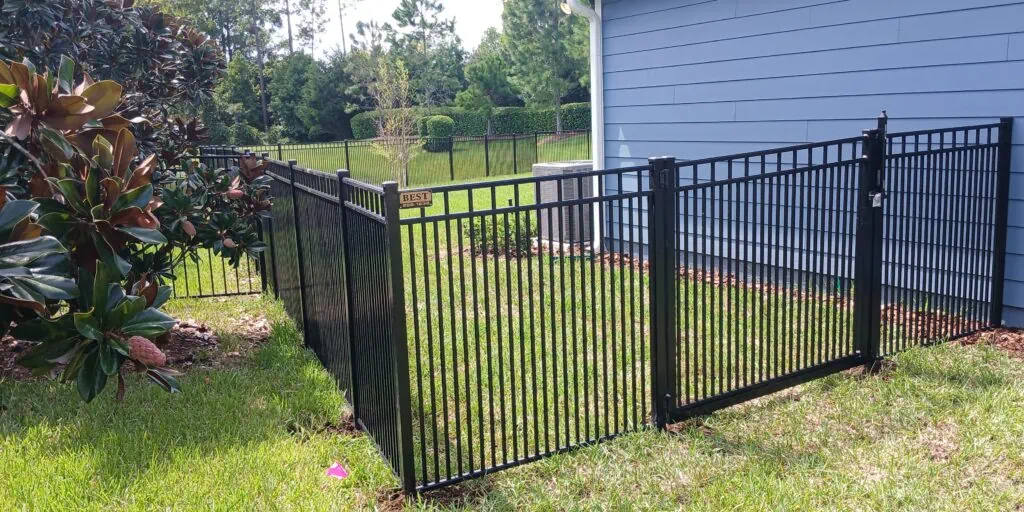 Black aluminum fence next to a beautiful blue home