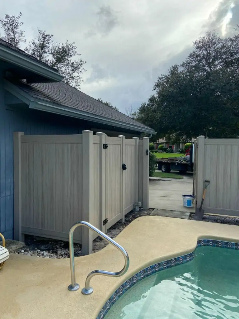 Custom vinyl fence alongside a backyard pool.  Good hiding place for the pool pump.