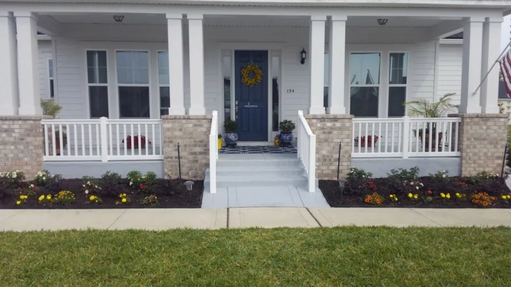 Front porch with stairs and pillars with hand rails.
