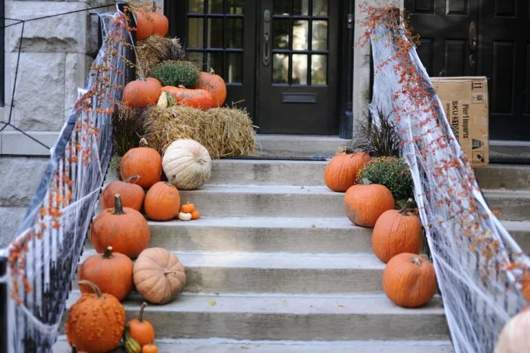 Front porch and doorway decorated with many pumpkins.