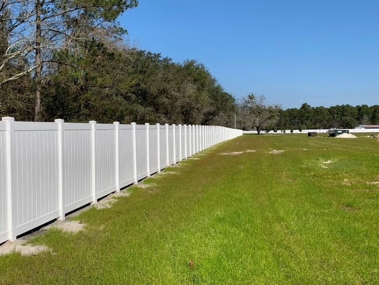 White vinyl fence surrounding large property area.