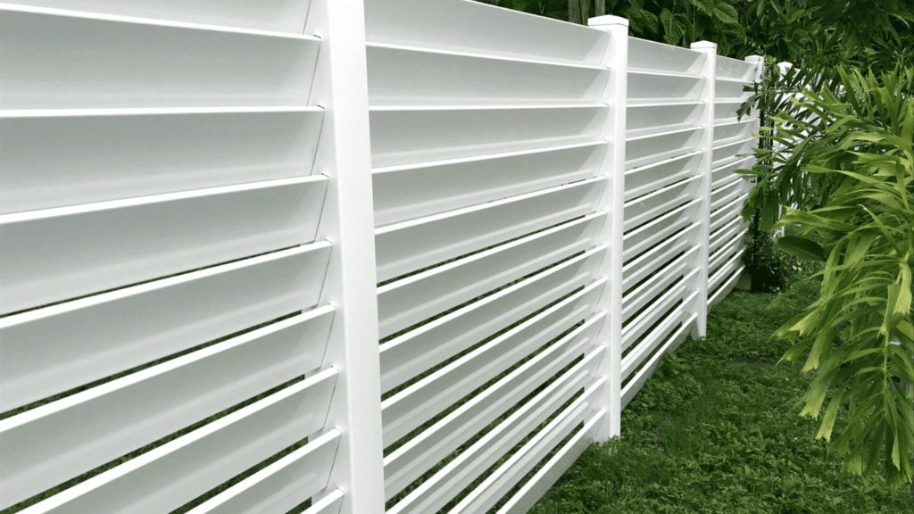 White vinyl fence and pretty green grass and scrubs.