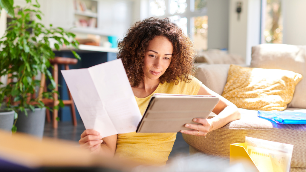 Lady with paper in her hand and reading something on a tablet.