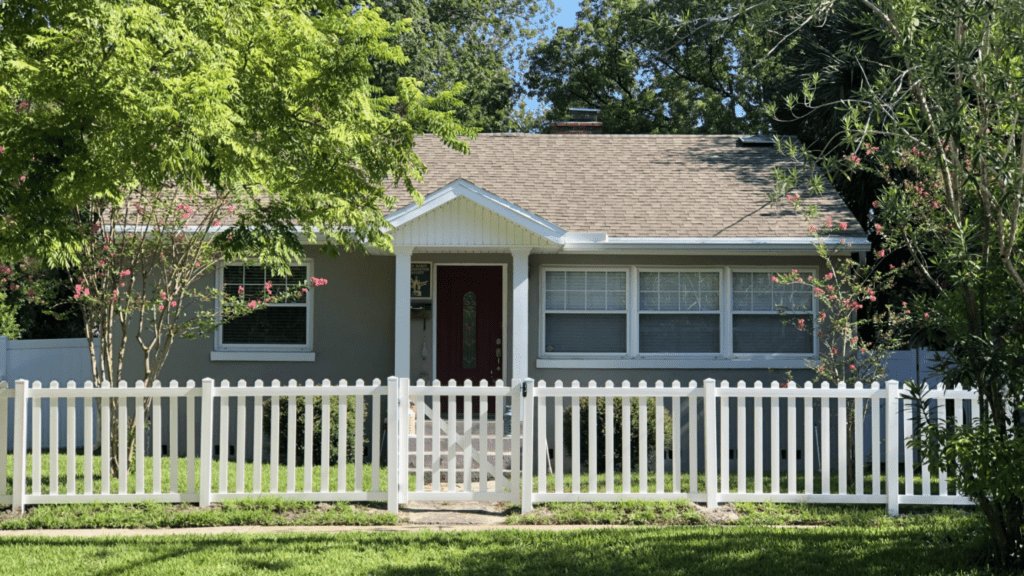 Small house with a white picket fence along the front yard