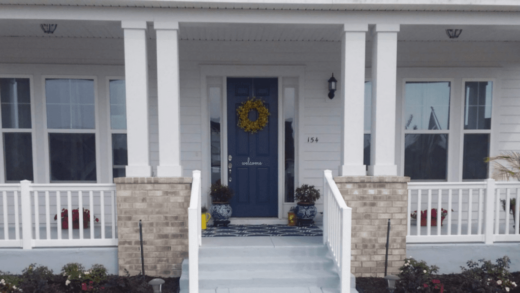 Pretty front porch with blue door and white railings.