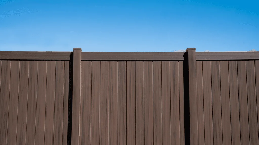 Brown Vinyl Fence with blue sky above.