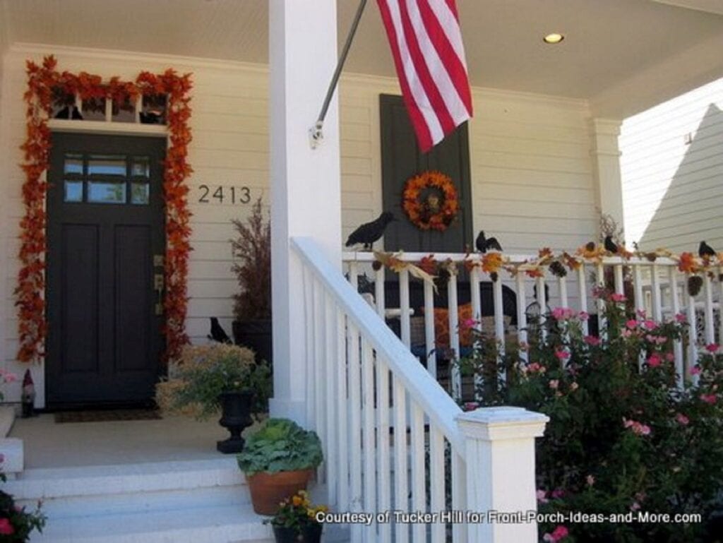 Front porch with fall decorations on railing and front door.