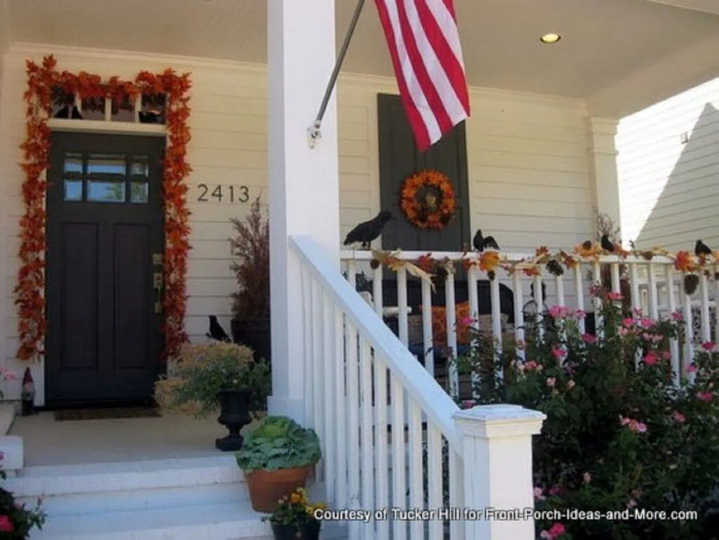 Front porch with fall decorations on railing and front door.