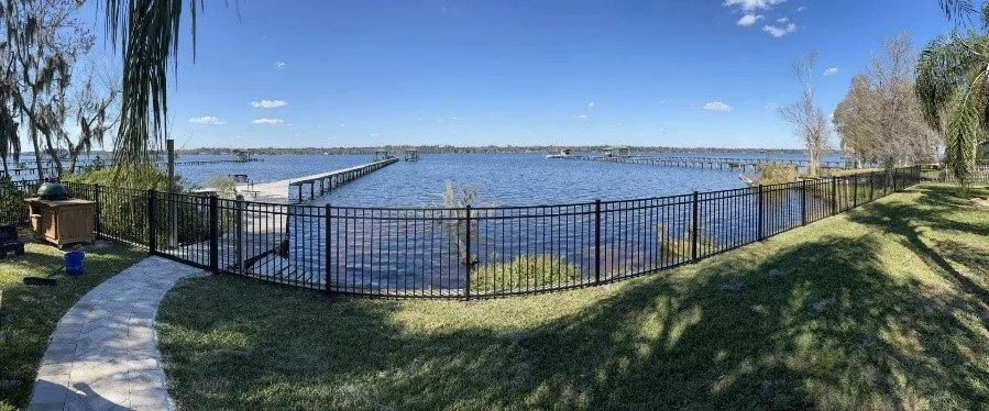 Black aluminum fence along river by dock and walkway