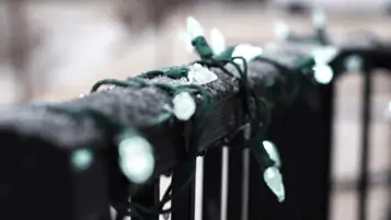 A black fence with white lights on it.