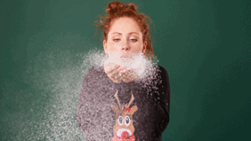 Lady blowing fake snow into the air.